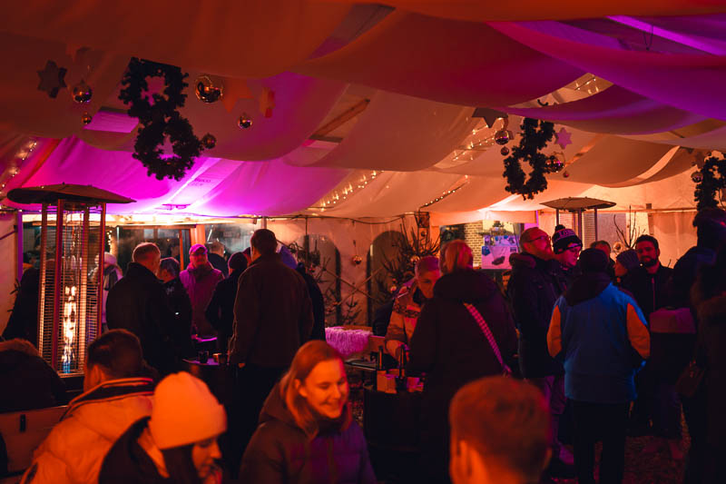 Feiernde Gäste im beleuchteten Winterzelt